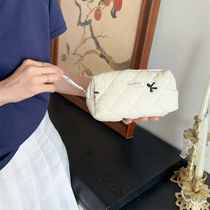 Quilted bow embroidery makeup bag in off-white finish with elegant zipper closure