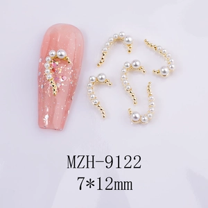 Detailed view of C-shaped nail art charms with white pearls and gold metal base