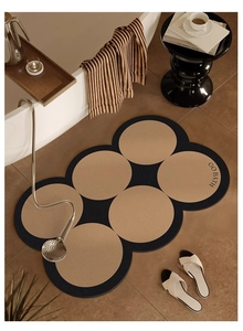 Modern irregular round beige diatom mud bath mat with GO BATH text on tiled floor