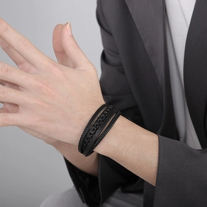 Detail of multi-layer black braided leather bracelet with magnetic steel clasp on wrist