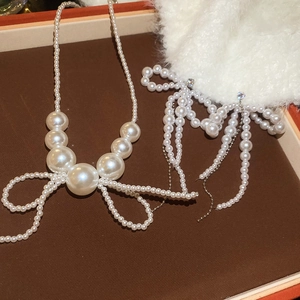 Macro detail of elegant pearl bow necklace and earrings set inside a premium gift box