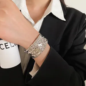 Silver wide cuff bracelet with irregular molten texture on a model wearing a suit