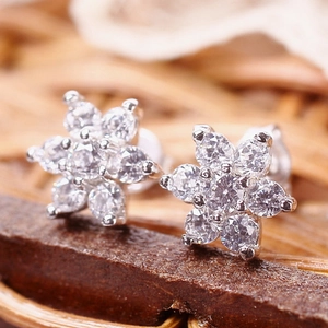 Macro shot of silver flower earrings with sparkling cubic zirconia on wood background