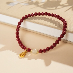Macro view of cinnabar bracelet with white jade bead and gold gourd lucky charm