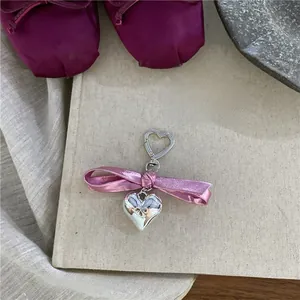 Detail of pink satin bow and silver heart pendant on a vintage book backdrop