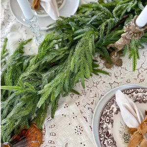 Lush green PE artificial Christmas garland on vintage table with lace and candles