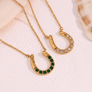 Detail of horseshoe pendants in 18K gold plated steel with clear and green crystals