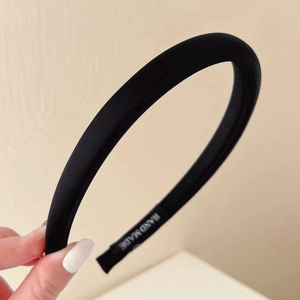 Close-up of black satin padded headband with handmade label held by hand