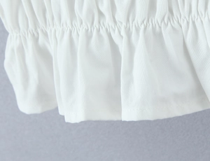 Detailed close-up of white lace set featuring elastic pleated texture and ruffled hems