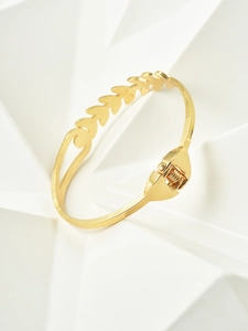 Detail of gold wheat leaf textured spring bangle with polished metal finish