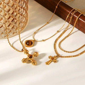 Close-up of golden multi-layer tiger eye stone cross necklaces on a wooden tray