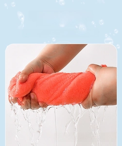 Close-up showing the strong water absorption of the thick coral fleece towel in orange