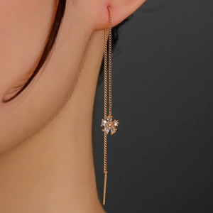 Close-up of golden long tassel drop earrings with sparkling zircon flower on a model