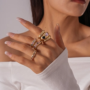Detail shot of multi-layered gold rings with purple and pink gems worn on a hand