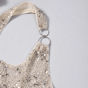 Dettaglio ravvicinato di tessuto con paillettes oro champagne e anelli metallici di aggancio