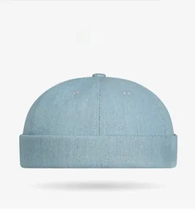 Detail of light blue washed denim skull cap with red embroidery and brimless design