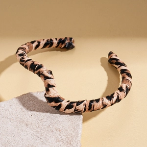 Macro detail of twisted leopard print leather texture on geometric open bracelet