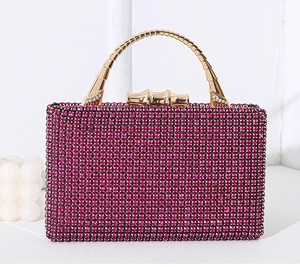 Macro detail of luxury fuchsia rhinestone evening clutch bag with gold metallic handle