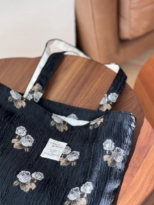 Close-up of black jacquard rose pattern texture and branded label on underarm bag