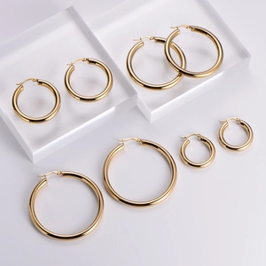 Set of four polished 18k gold plated hollow hoop earrings in varied sizes on white background