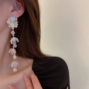 Detailed view of floral tassel earrings with white frosted petals and blue gemstones