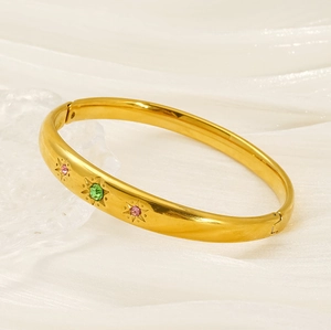 Detailed macro view of gold-plated bangle with colorful starburst zirconia inlays