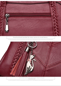 Close-up of wine red quilted faux leather handbag with a cat charm and back zipper pocket