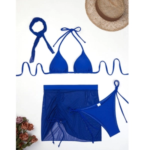 Flat lay of blue four-piece bikini set with mesh skirt, hair tie, and straw hat accents