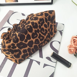 Close-up of leopard print fabric hair tie on a fashion magazine with rose and lipstick