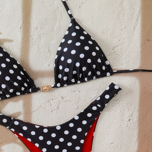 Close-up of polka dot bikini with sun-shaped gold buckle and red lining detail