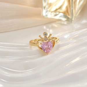 Macro detail of gold crown ring with a pink heart gemstone and micro-pave crystals