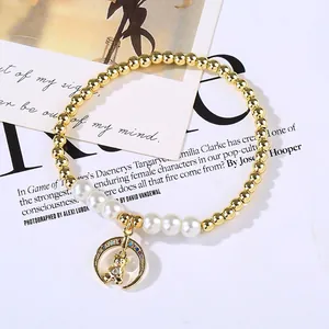 Detail of gold beaded pearl bracelet with micro-pave moon and bear charm pendant