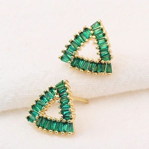Macro detail of gold triangle earrings featuring emerald green emerald-cut gemstones