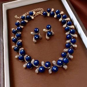Macro shot of dark blue resin drop jewelry set with gold vine details and rhinestones