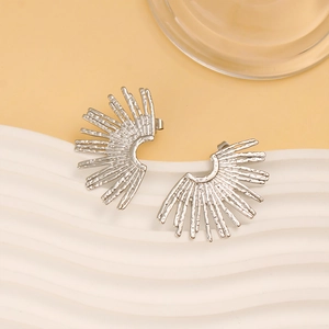 Detail view of silver fan-shaped earrings with unique hammered texture on white tray