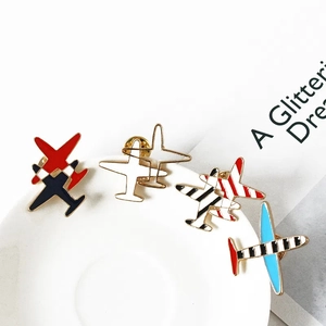 Lot de quatre broches avion en émail avec rayures et finitions dorées sur assiette