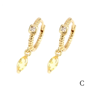 Macro detail of 18K gold earrings with yellow marquise-cut and white square zirconias