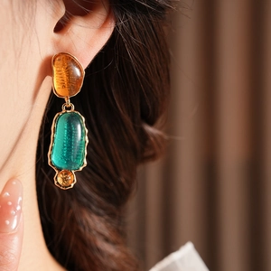 Close-up of vintage resin earrings with amber and green stones in gold setting