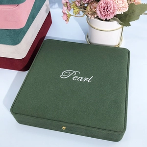 Detail of dark green velvet jewelry box with gold clasp and Pearl logo engraving