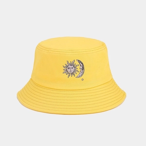 Close-up detail of yellow bucket hat featuring embroidered sun and moon art design