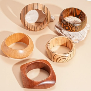 Detail view of various geometric wooden bangles with natural grain textures on stone decor