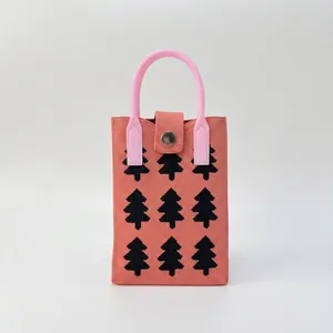 Detail of coral pink knitted phone bag with black pine patterns and round handle