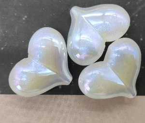 Dettaglio macro di tre perle in resina a forma di cuore con finitura perlata