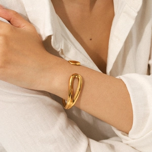 Detailed view of an elegant gold hollow teardrop bangle on a female wrist