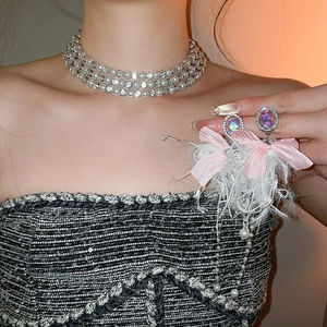 Detail of multilayer pearl necklace and pink ribbon bow with feathers and gemstone