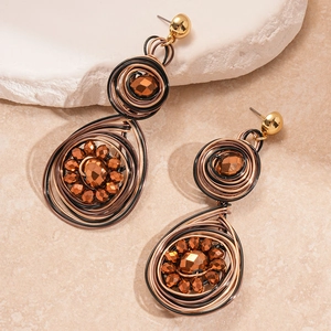 Macro detail of handmade wire-wrapped stud earrings with bronze beads and teardrop shapes