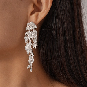 Detailed view of silver leaf tassel earrings with pave-set rhinestones on a model's ear