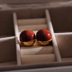 French vintage gold ball earrings with white enamel finish on a beige jewelry display