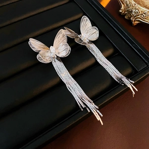 Detail von silbernen Schmetterlings-Ohrringen mit glitzernden Quasten auf Schmucktablett