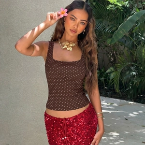 Dettaglio di un top marrone a pois con gonna rossa di paillettes e collana dorata elegante